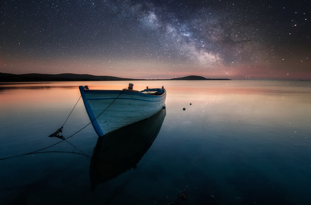 Boat in the black sea under the Milky Way