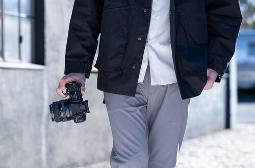 man walking holding a Fujifilm GFX 100S