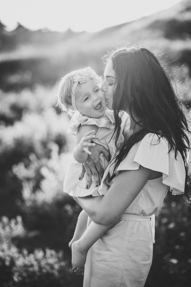 Mother kissing baby daughter bw