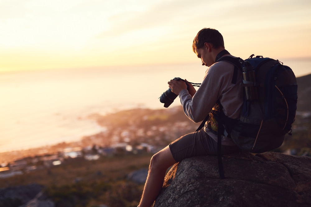 Photographer looking at back of camera at sunset