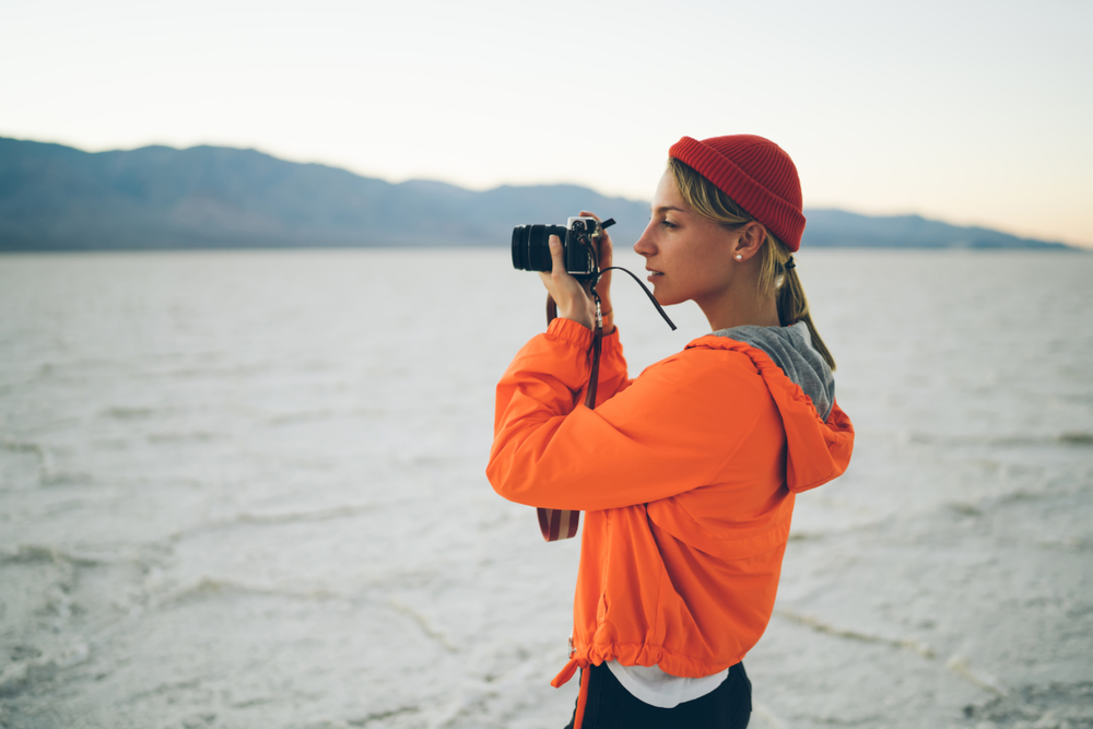 photographer taking pictures of nature and landscape in desert wearing an orange jacket