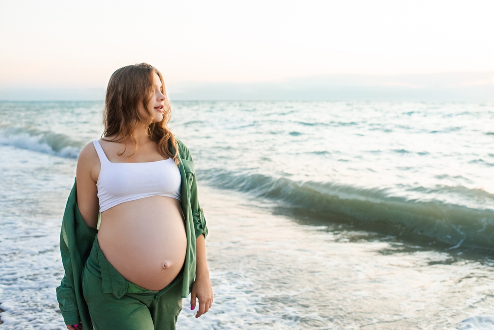 Pregnant woman walking in the ocean waves