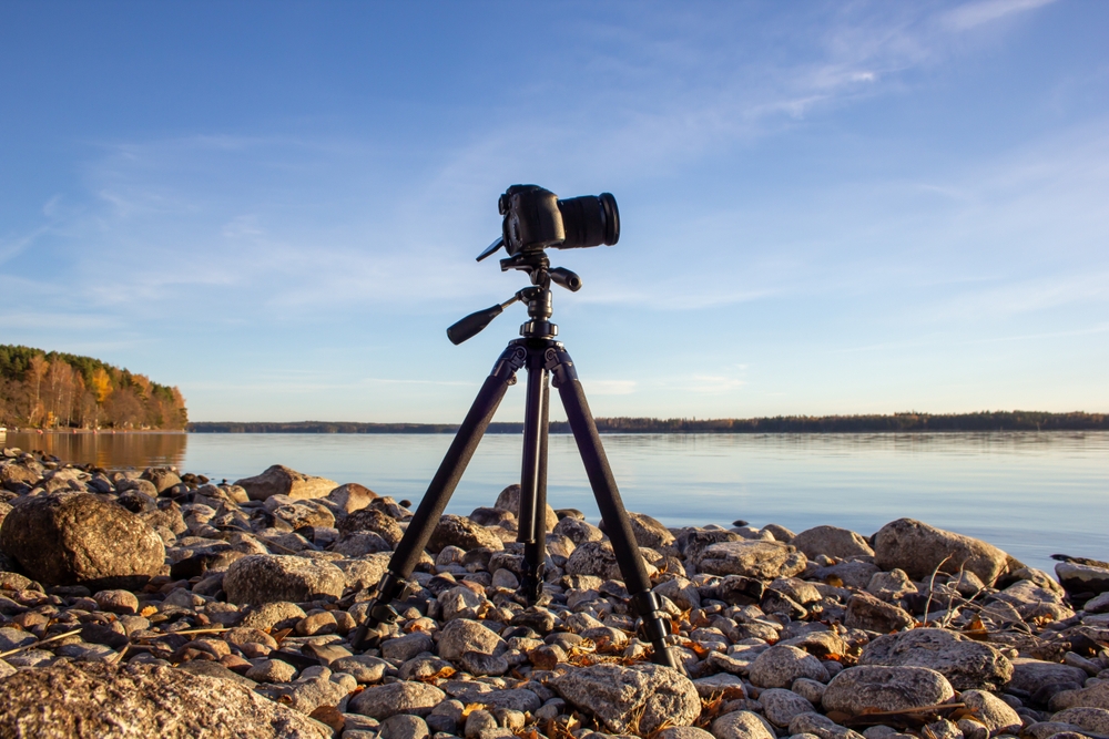 Professional camera on tripod at rocky lakeside