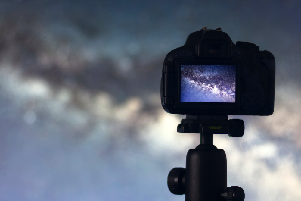 Silhouette of camera with milky way on its view screen